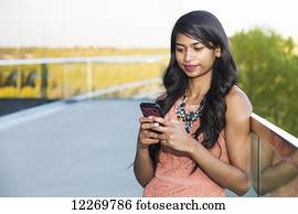 Young professional businesswoman texting on her smart phone; Edmonton, Alberta, Canada