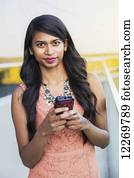 Young professional businesswoman texting on her smart phone; Edmonton, Alberta, Canada Young professional businesswoman texting on her smart phone; Edmonton, Alberta, Canada