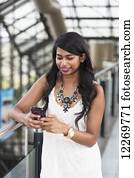 Young professional businesswoman texting on her smart phone in office building; Edmonton, Alberta, Canada