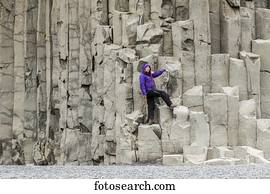 A female tourist poses on the basalt rock columns on the Reynisfjara beach in Southern Iceland; Iceland