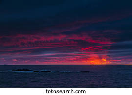 Clouds glowing a bright pink on the horizon over water; Bonavista, Newfoundland, Canada