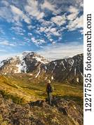 Hiker on rock outcrop overlooks Powerline Pass valley and trail, Chugach State Park, Southcentral Alaska