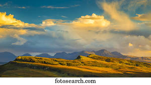 Sunlight illuminating the mountainous landscape and clouds; Isle of Skye, Scotland