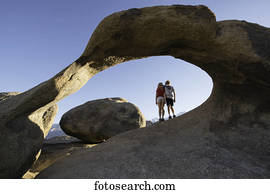 Young children standing under a natural rock arch, Alabama Hills; California, United States of America