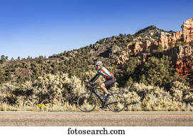 A senior man cycles in Zion Nation Park; Utah, United States of America