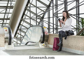Business woman texting on her smart phone after taking a shopping break during her work day; Edmonton, Alberta, Canada Business woman texting on her smart phone after taking a shopping break during her work day; Edmonton, Alberta, Canada