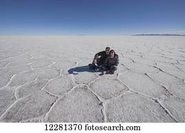 Couple sitting on the salt flats of the Salar de Uyuni; Bolivia