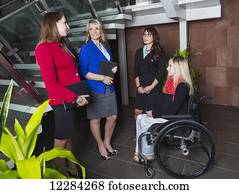 Four professional business women in the lobby of an office, one of which is a paraplegic in a wheelchair; St. Albert, Alberta, Canada