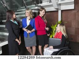 Four professional business women in the lobby of an office, one of which is a paraplegic in a wheelchair; St. Albert, Alberta, Canada