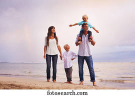 Happy young family on the beach at sunset