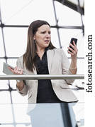 Mature business woman shocked at message received on her smart phone; Edmonton, Alberta, Canada