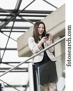 Mature business woman taking a break and texting on her smart phone; Edmonton, Alberta, Canada