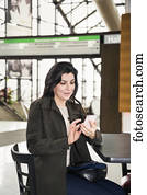 Mature business woman texting while taking a break in the atrium of an office building; Edmonton, Alberta, Canada