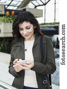 Mature business woman texting while taking a break in the atrium of an office building; Edmonton, Alberta, Canada