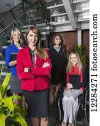 Portrait of a professional business woman with her team in the lobby of an office, one of which is a paraplegic in a wheelchair; St. Albert, Alberta, Canada