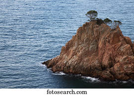 Rugged rock with trees on the ridge out in the ocean; Gerone, Catalonia, Costa Brava, Spain