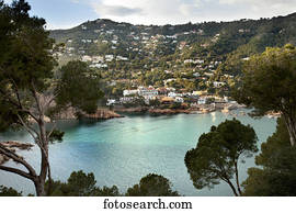 Turquoise water in a lake with houses on a hillside; Gerone, Catalonia, Costa Brava, Spain