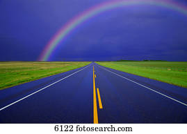 Two-lane road in country on rainy day with rainbow