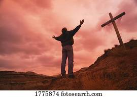 Man at cross with raised arms