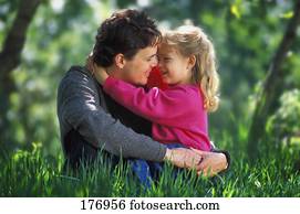 Father and daughter hugging in tall grass in park