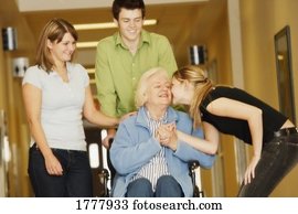 Young adults visiting a senior woman in a wheelchair