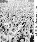 Large crowd of people with their arms raised