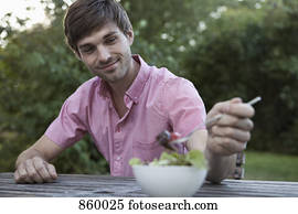 A man eating at a table outdoors, non-urban scene