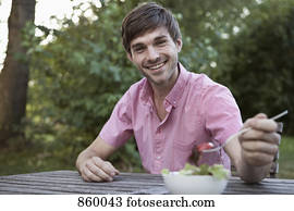 A man eating at a table outdoors, non-urban scene