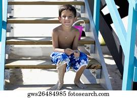 Portrait of a boy sitting on a staircase of a lifeguard hut