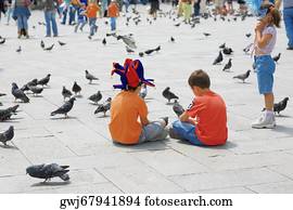 Rear view of two boys sitting with pigeons in front of them, Venice, Veneto, Italy