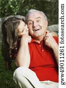 Portrait of a senior man smiling with his granddaughter kissing him