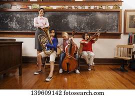 Students playing musical instruments with their teacher standing beside them
