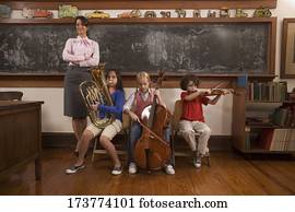 Students playing musical instruments with their teacher standing beside them