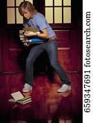 Teenage boy trying to balance books in a school corridor