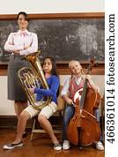 Two girls playing musical instruments with their teacher standing beside them