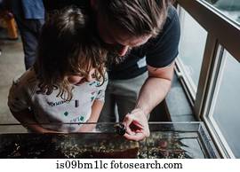 Father and daughter discovering sea life in aquarium
