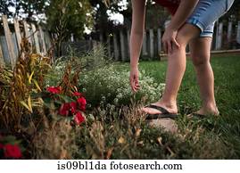 Girl reaching out for flower in garden