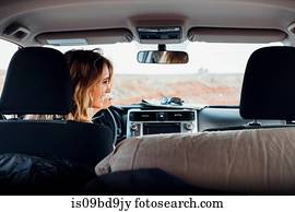 Young woman driving vehicle in remote setting, rear view, vehicle interior, Mexican Hat, Utah, USA
