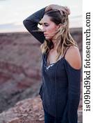 Young woman in remote setting, looking at view, holding hair off face, Mexican Hat, Utah, USA