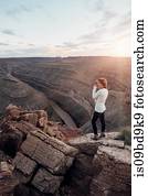 Young woman in remote setting, standing on rocks, looking at view, Mexican Hat, Utah, USA