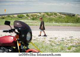 Boy walking past motorbike