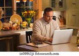 Mature man working on laptop in kitchen