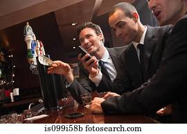 Three businessmen getting drinks at a bar