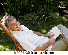 Man sitting on deckchair in garden with book
