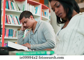 University students reading textbooks in college library