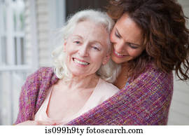 Senior woman and daughter embracing on porch, portrait