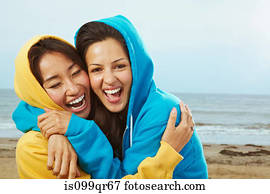 Two young women in hooded tops on beach