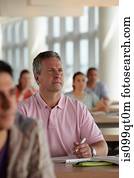 Mature students in class, man making notes