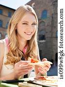 Young woman at restaurant outdoors with slice of pizza