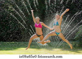 Teenage girls playing in sprinkler